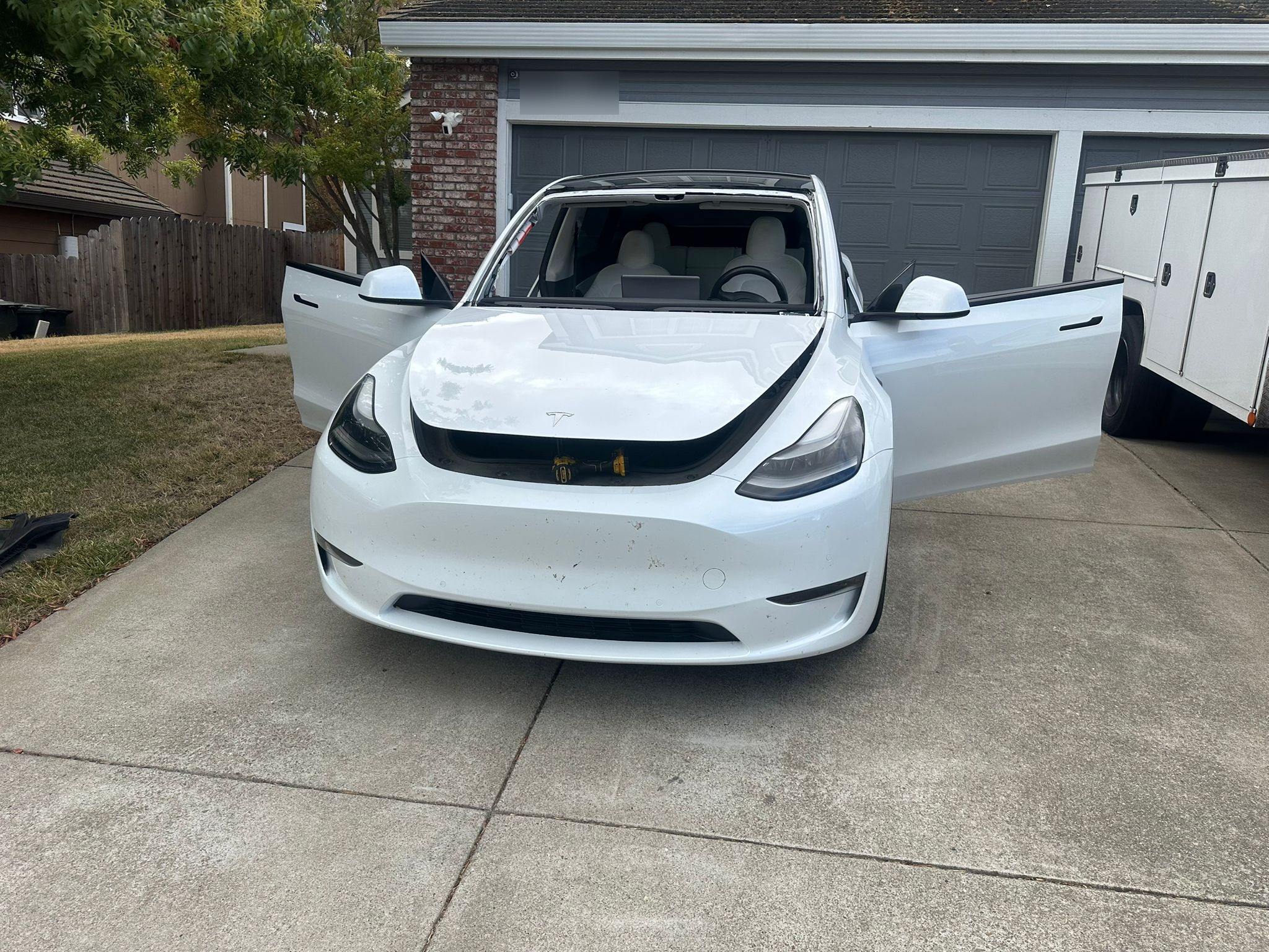 White Tesla Model Y in driveway during mobile windshield replacement service by Xpro Auto Glass